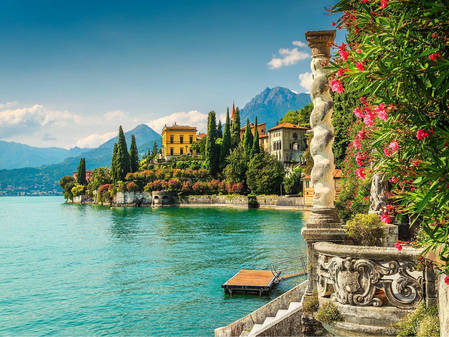 A lakeside villa among cypress trees and flowering gardens on the turquoise water of Lake Como